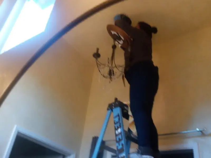 Electrician installing a chandelier in a Gladewater residence